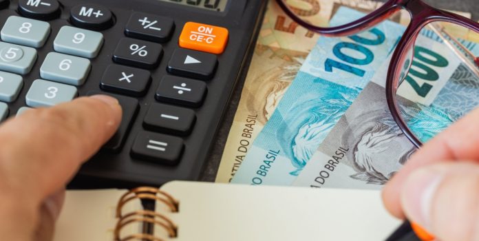 Imagem de pessoa fazendo contagem de impostos na calculadora. Matéria: Quais são os novos impostos sobre apostas esportivas?