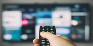 TAPPP e a nova era no entretenimento esportivo: “Queremos que a tela da TV faça parte da experiência” imagem de um telespectador assistindo televisão com um controle remoto na mão, para falar sobre a nova tecnologia da TAPPP