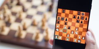BETBY expande portfólio de apostas em xadrez antes da estreia na Copa do Mundo de eSports Foto de celular com jogo de xadrez on-line, com tabuleiro desfocado atrás