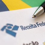 Logo da Receita Federal do Brasil no papel e uma caneta
