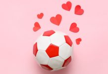 Bola de futebol e corações vermelhos com fundo rosa