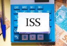 Sigla ISS no papel em cima da calculadora, com notas de dinheiro ao lado