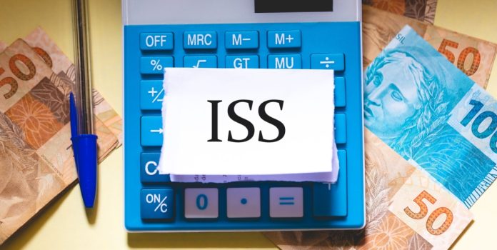 Sigla ISS no papel em cima da calculadora, com notas de dinheiro ao lado