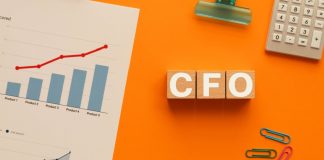 Escrivaninha com gráfico, clipes, calculadora e a sigla CFO em cubos de madeira
