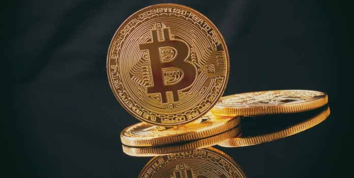 sbc-summit-2025-entrevista-dee-maher- Moeda dourada com o símbolo da Bitcoin