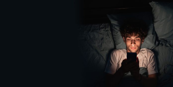 vicio-apostas-online-preocupa-vereador-edson-azeredo Rapaz mexendo no celular no escuro deitado na cama