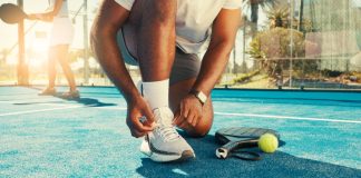 Comissão do Esporte aprova proibição de bloqueio de recursos das apostas destinados ao esporte Homem amarrando os tênis com raquete e bola ao lado