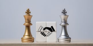 MC Games e EBAC fecham parceria para fortalecer proteção ao jogador Dois reis de xadrez com blocos de aperto de mão entre eles