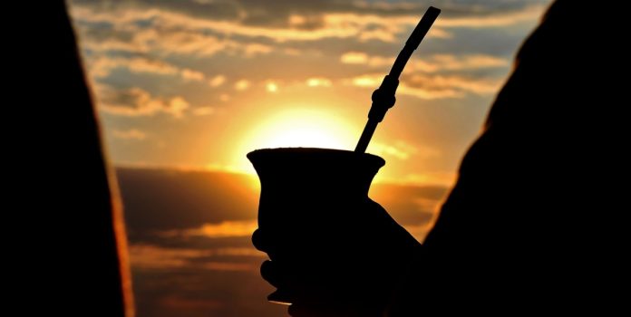Silhueta de pessoa bebendo chimarrão perto do rio Guaíba em Porto Alegre, capital do RS