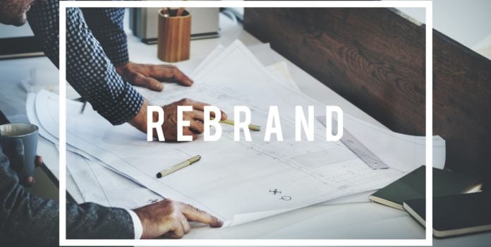 open-gaming-nova-identidade-corporativa Pessoas analisando papéis com 'Rebrand' escrito no meio da imagem