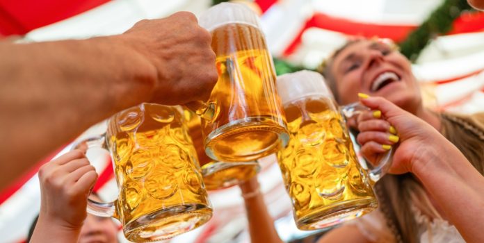 reals-acordo-de-patrocínio-oktoberfest-blumenau Grupo de amigos brindando com canecas de cerveja