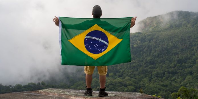 brasileiros-apostas-online-pesquisa-poderdata Homem na montanha segurando a bandeira do Brasil e olhando para o céu