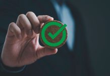 Empresário segurando emblema redondo de madeira com símbolo de marca de verificação verde
