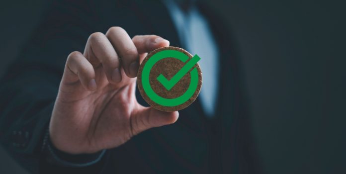gli-reconhece-data.bet-no-brasil Empresário segurando emblema redondo de madeira com símbolo de marca de verificação verde