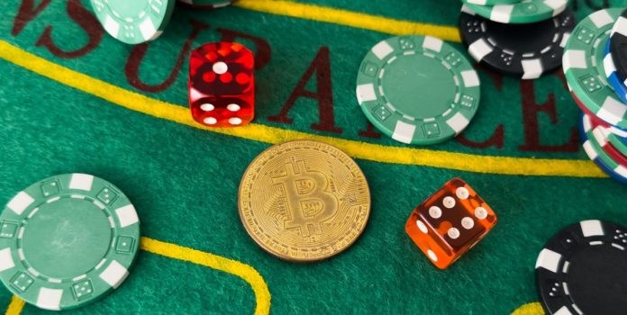 Fichas de cassino, moeda com símbolo da Bitcoin e dados de jogos