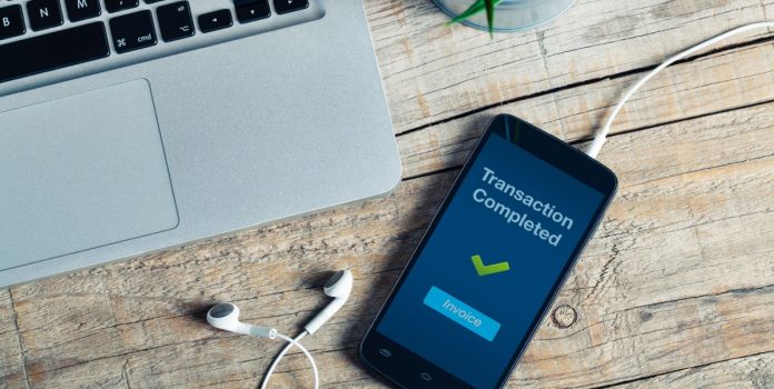 paag-analisa-comportamento-de-apostadores-brasileiros Smartphone sobre a mesa, ao lado de um notebook, com a mensagem de transação efetuada