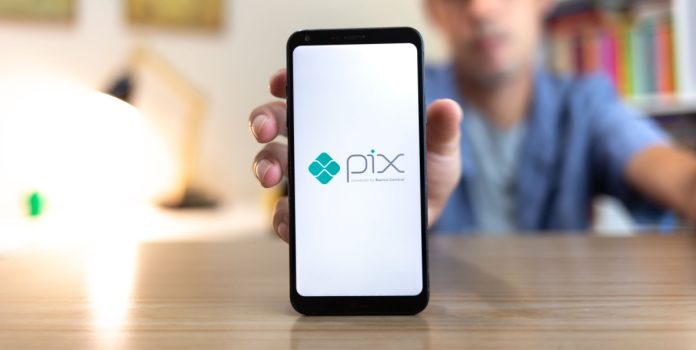 pagsmile-estudo-pix-apostas-2025 Homem segurando celular com o logo do Pix na tela