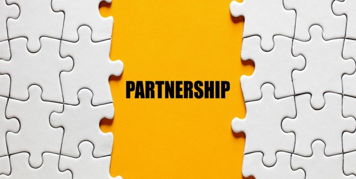 salsa-technology-parceria-sprint-gaming Fundo laranja escrito "Partnership" entre peças de quebra-cabeça