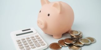 Cofre de dinheiro em formato de porco, calculadora e moedas sobre a mesa