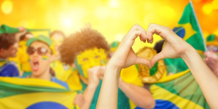 Silvia-Paleari,-IBIA,-comenta-avanço-do-Brasil-na-integridade-esportiva Brasileiros comemorando com bandeira, máscaras e fazendo coração com as mãos