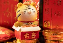 Tigre chinês em miniatura posicionado em cimas de moedas de ouro