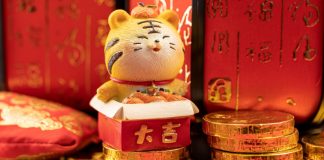 Tigre chinês em miniatura posicionado em cimas de moedas de ouro