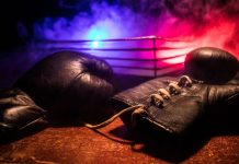 Luvas de boxe e um ringue de luta vazio atrás