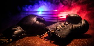 Luvas de boxe e um ringue de luta vazio atrás