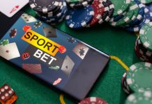 Fichas de cassino e celular com a tela apresentando "apostas esportivas" em inglês sobre a mesa de jogo