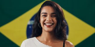 Mais apostas, menos riscos: Beanalytic observa mudança no comportamento dos brasileiros Mulher sorrindo com a bandeira do Brasil no fundo
