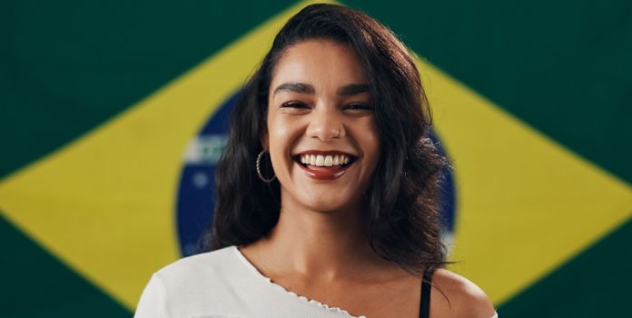 pesquisa-apostas-brasil-beanalytic Mulher sorrindo com a bandeira do Brasil no fundo
