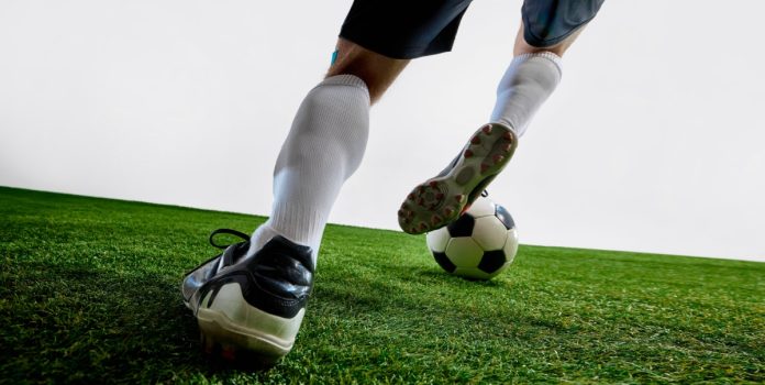Pernas de homem jogando futebol no gramado