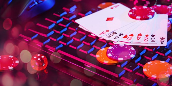 Greentube-fortalece-presença-na-América-Latina-com-Brazino777 Arranjo de fichas de poker e de cartas sobre o teclado do computador