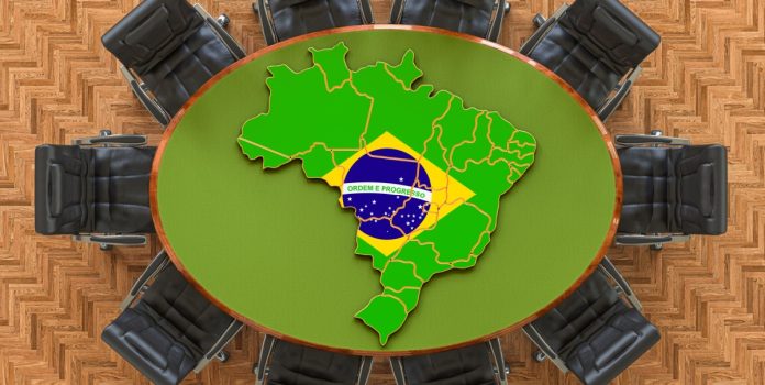 Mesa vista de cima com dez cadeiras ao redor e o mapa do Brasil sobre ela