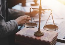 SPA reforça exigências administrativas para operadores de apostas Homem sentado em escritório, com papéis sobre a mesa e a balança representando a advocacia