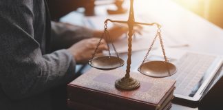 SPA reforça exigências administrativas para operadores de apostas Homem sentado em escritório, com papéis sobre a mesa e a balança representando a advocacia