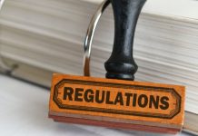 Carimbo escrito regulations com fichário cheio de folhas atrás dele