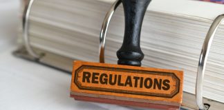 Carimbo escrito regulations com fichário cheio de folhas atrás dele