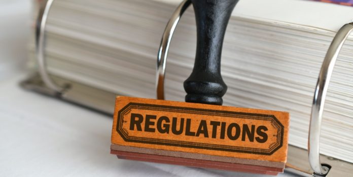 Carimbo escrito regulations com fichário cheio de folhas atrás dele