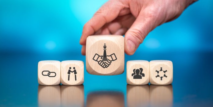 optimove-e-salsa-technology-firmam-parceria-estratégica-latam Mão segurando um dos blocos de madeira com símbolos representando aliança estratégica