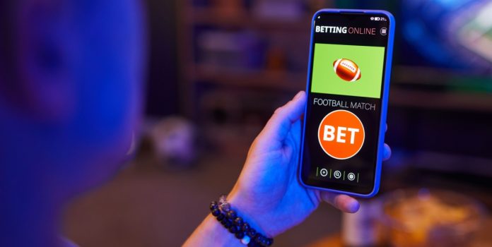 pl-5963-2025-lúcio-mosquini Mão segurando celular com imagem de 'bet'