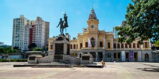 Foto tirada de uma praça em Belo Horizonte, onde é possível ver uma estátua ao centro e uma igreja ao fundo.
