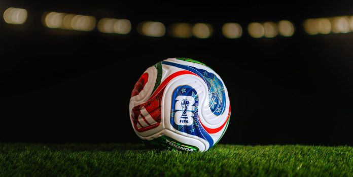 Bola de futebol branca da Adidas, com detalhes em azul e vermelho, que será utilizada na Copa do Mundo 2026.