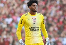 Hugo Souza, um homem negro alto, vestido a camisa amarela de goleiro do Corinthians, cujo patrocínio máster é a Esportes da Sorte.