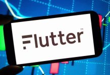 Mão segurando um smartphone cuja tela mostra a palavra Flutter.
