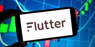 Mão segurando um smartphone cuja tela mostra a palavra Flutter.