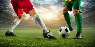 A imagem mostra as pernas de 2 jogadores e um está tentando driblar o outro.