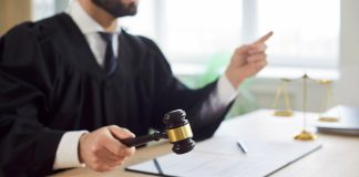 Juiz, um homem, batendo o martelo num tribunal de justiça.