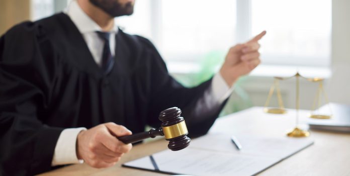 Juiz-Tribunal Juiz, um homem, batendo o martelo num tribunal de justiça.