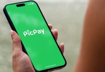 PicPay pede IPO nos EUA e inclui holding de apostas no Brasil em estratégia Mulher segurando celular aberto no aplicado do PicPay, que pediu IPO nos EUA com holding de apostas online